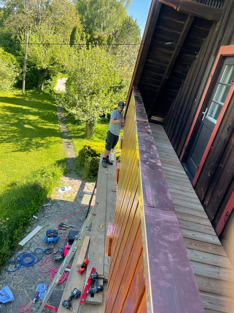 Handwerker auf dem Gerüst bei der Montage einer Holzverkleidung mit Kupferabdeckung am Balkon von Schreinerei Ammersee.