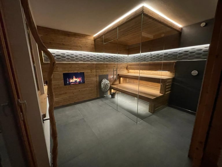 Moderne Innensauna mit Eckverglasung, ausgestattet mit rustikaler Holzverkleidung und indirekter LED-Deckenbeleuchtung