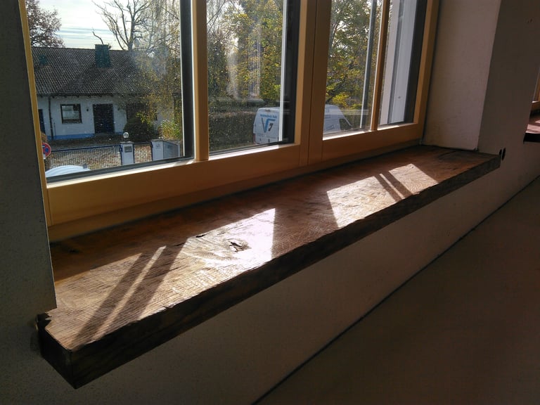 Sonnenlicht fällt durch ein Fenster auf eine rustikale Holzfensterbank.