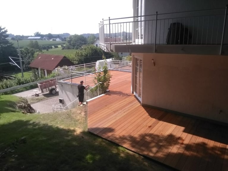 Großflächige Holzterrasse mit Geländer und Treppenaufgang im Außenbereich von Holztechnik Volk am Ammersee