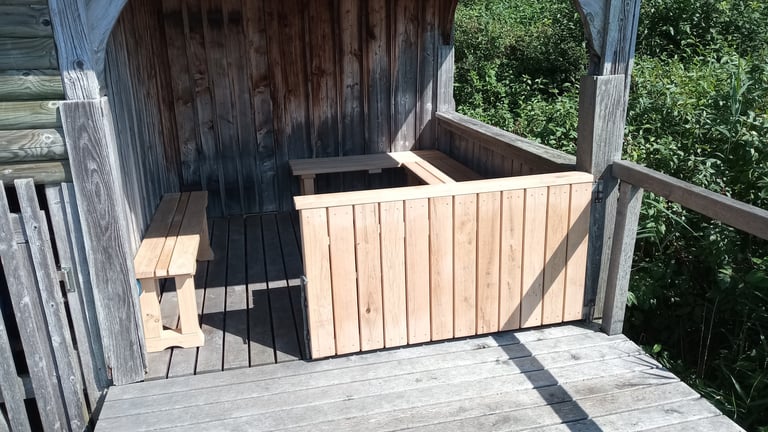 Überdachte Holz-Sitznische mit Bänken und neu montierter, heller Klapp-Brüstung aus senkrechten Latten.