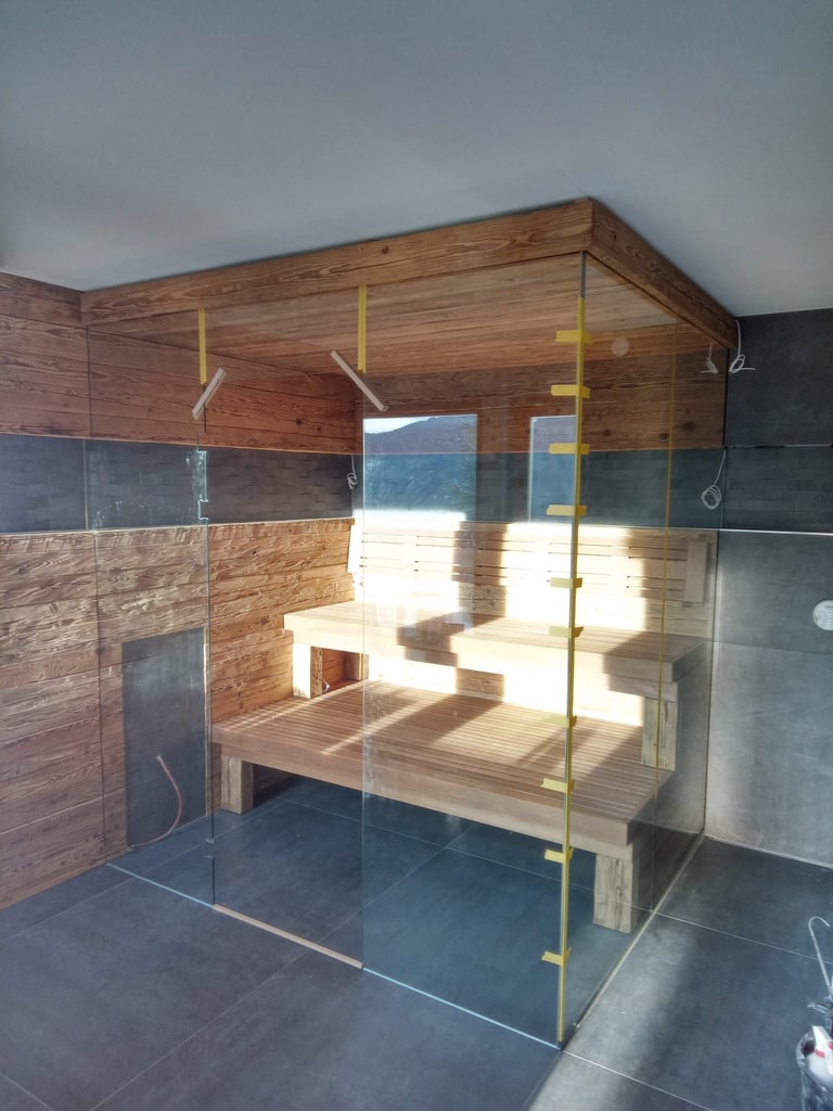 Holzsauna mit zweistufiger Bank hinter einer Glasabtrennung.