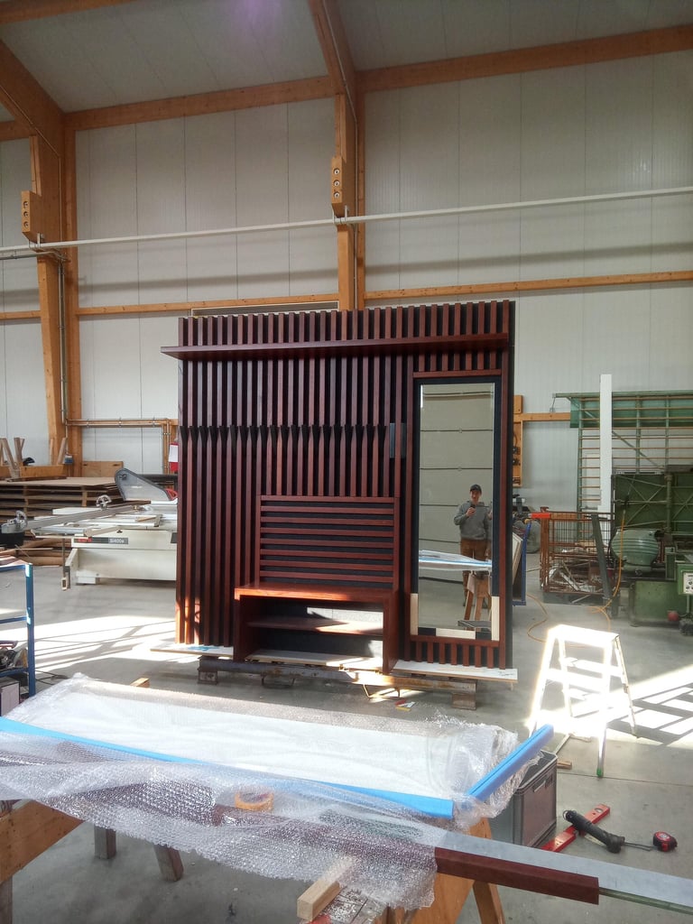 Große Lamellen-Holzwand mit integrierter Sitzbank und Spiegel in einer Werkstatt.