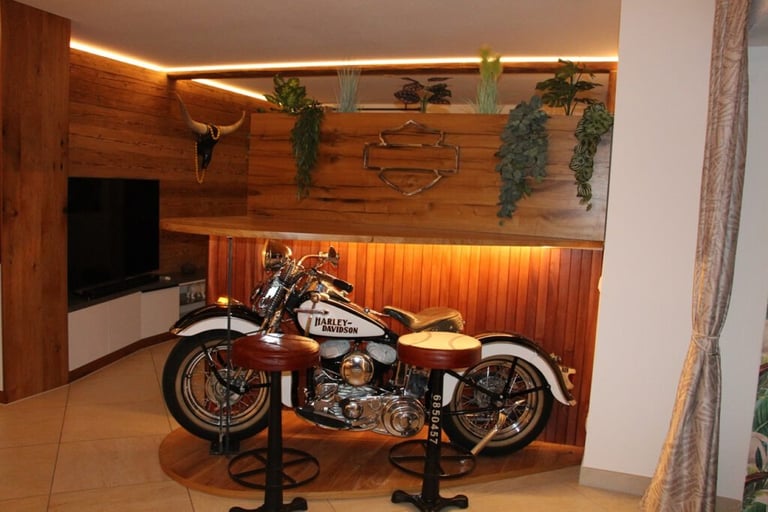 Hausbar mit integriertem Harley-Davidson als Thekenbasis, rustikaler Holzvertäfelung und stimmungsvoller LED-Beleuchtung