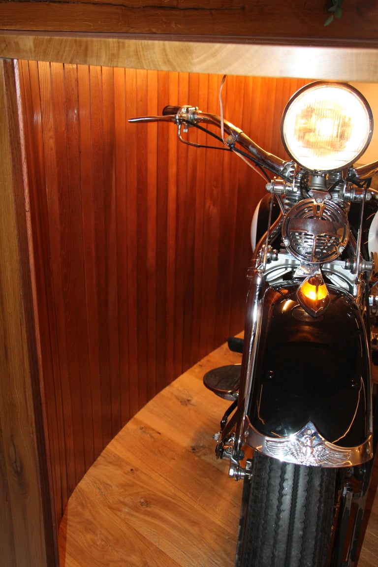 Beleuchteter Frontscheinwerfer und Chromteile des integrierten Motorrads vor Holztäfelung.