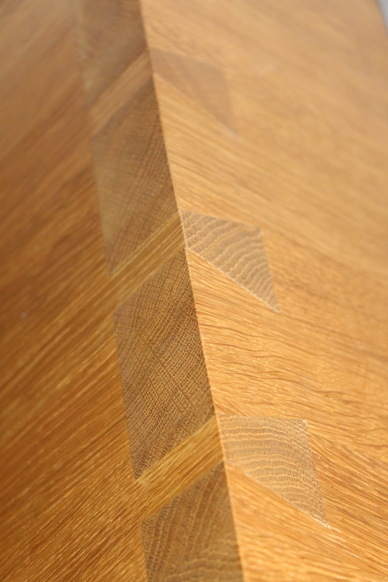 Detailaufnahme einer handwerklich präzisen Zinkenverbindung aus massivem Holz.