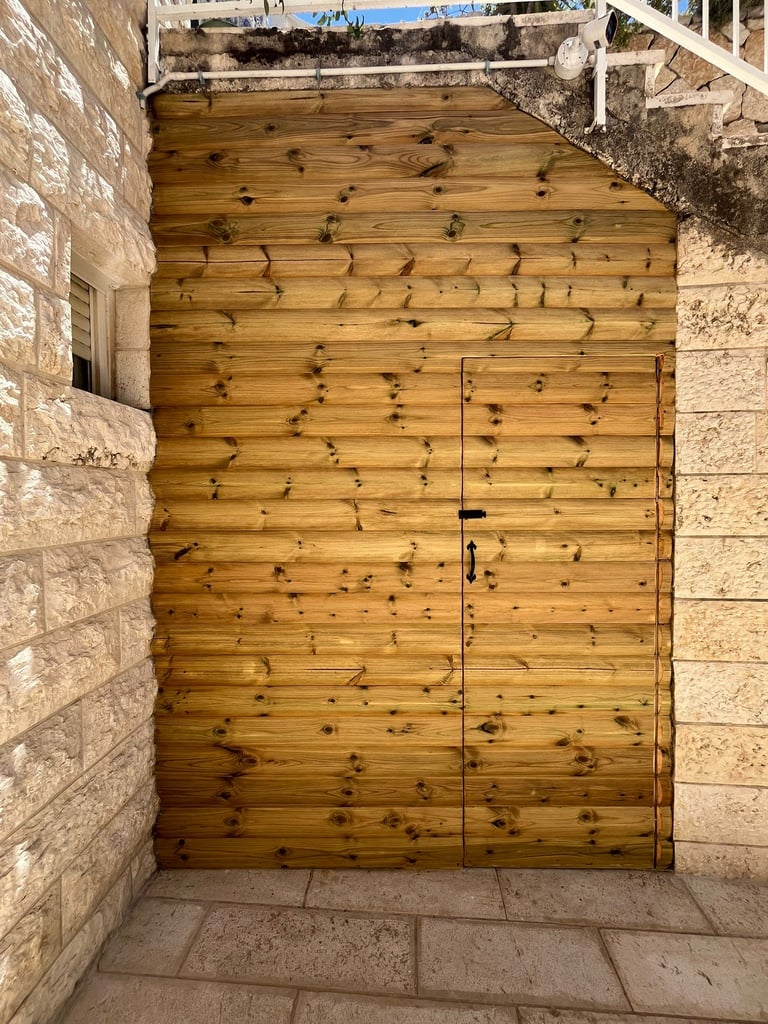 Rustic wooden storage door built into a natural stone wall with horizontal cedar planks.