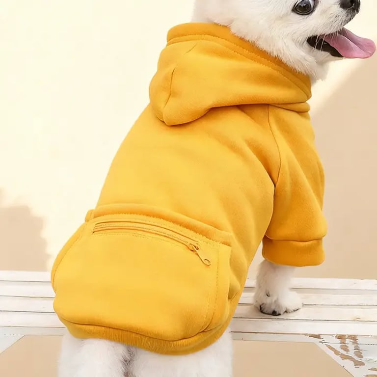 Perrito blanco que lleva una cómoda sudadera con capucha para mascotas de color amarillo mostaza, bolsillo con cremallera.