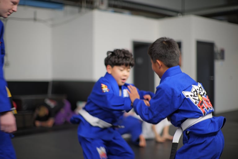 Kids BJJ class at RebelFire MMA Langley — young grapplers working grip fighting in the Gi under coac