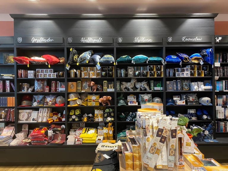 Harry Potter merchandise display with Gryffindor, Hufflepuff, Slytherin, and Ravenclaw house apparel and souvenirs.