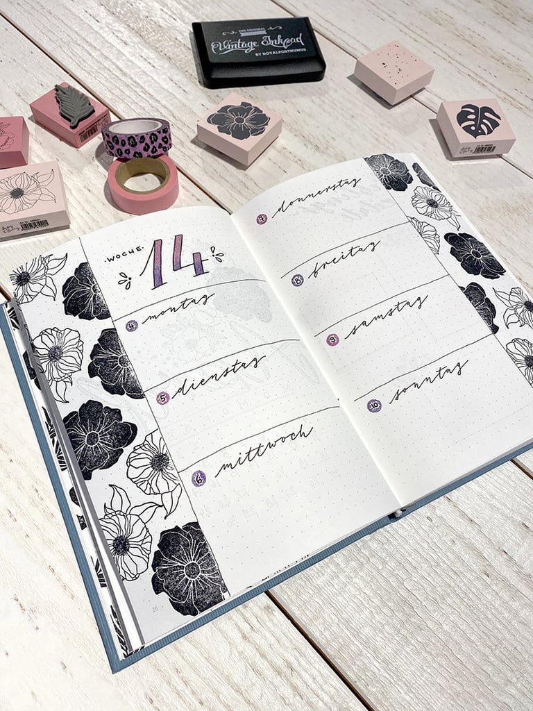 Bullet journal weekly spread with black floral stamps, washi tape, and hand-lettered German days.