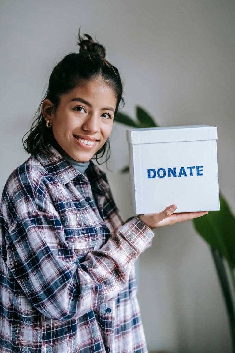 Una joven sostiene una caja blanca de donaciones benéficas para el apoyo a la comunidad.