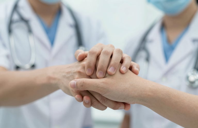 A close-up photo of two people's hands joined in a supportive gesture, set against a blurred medical background. Bright, high-key lighting to emphasize empathy and trust. Incorporates #EEF8F7.