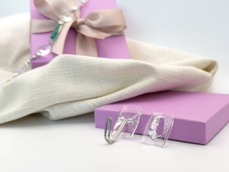 Clear adhesive wall hooks displayed on a purple gift box with white linen fabric.