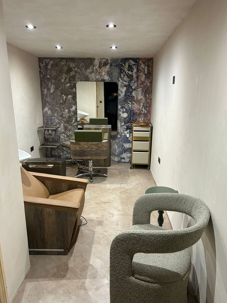 Modern interior of a hair salon finished with microcement, featuring professional chairs, a washbar.
