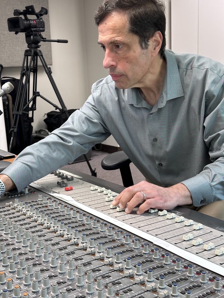 Audio engineer adjusting faders on a professional sound mixing console in a recording studio.