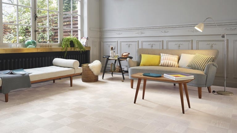 Modern living room with light oak parquet flooring, mid-century furniture, and grey wainscoting.