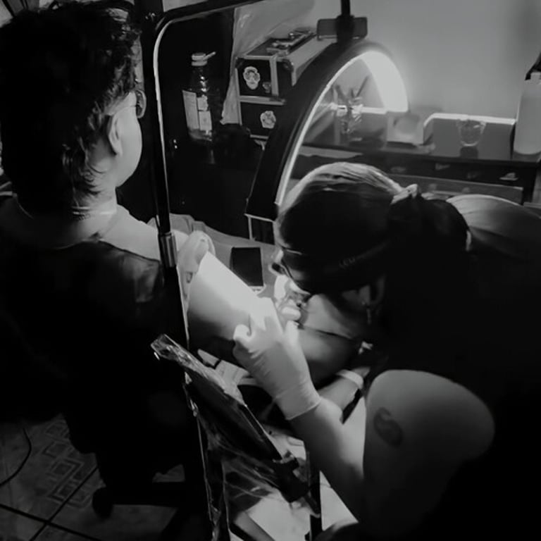 Tatuador profesional aplicando tinta en el brazo de un cliente bajo una iluminación brillante.