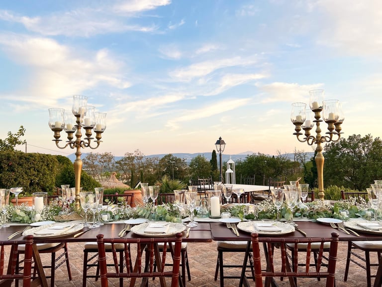 Elegant outdoor wedding reception table setting with gold candelabras and sunset views.