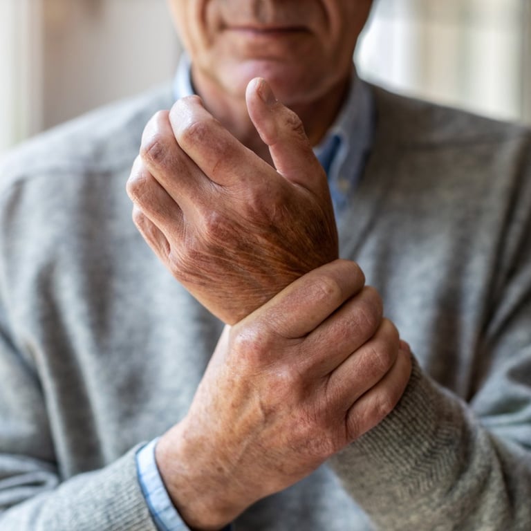 Senior man holding his painful wrist, demonstrating symptoms of arthritis or joint inflammation.