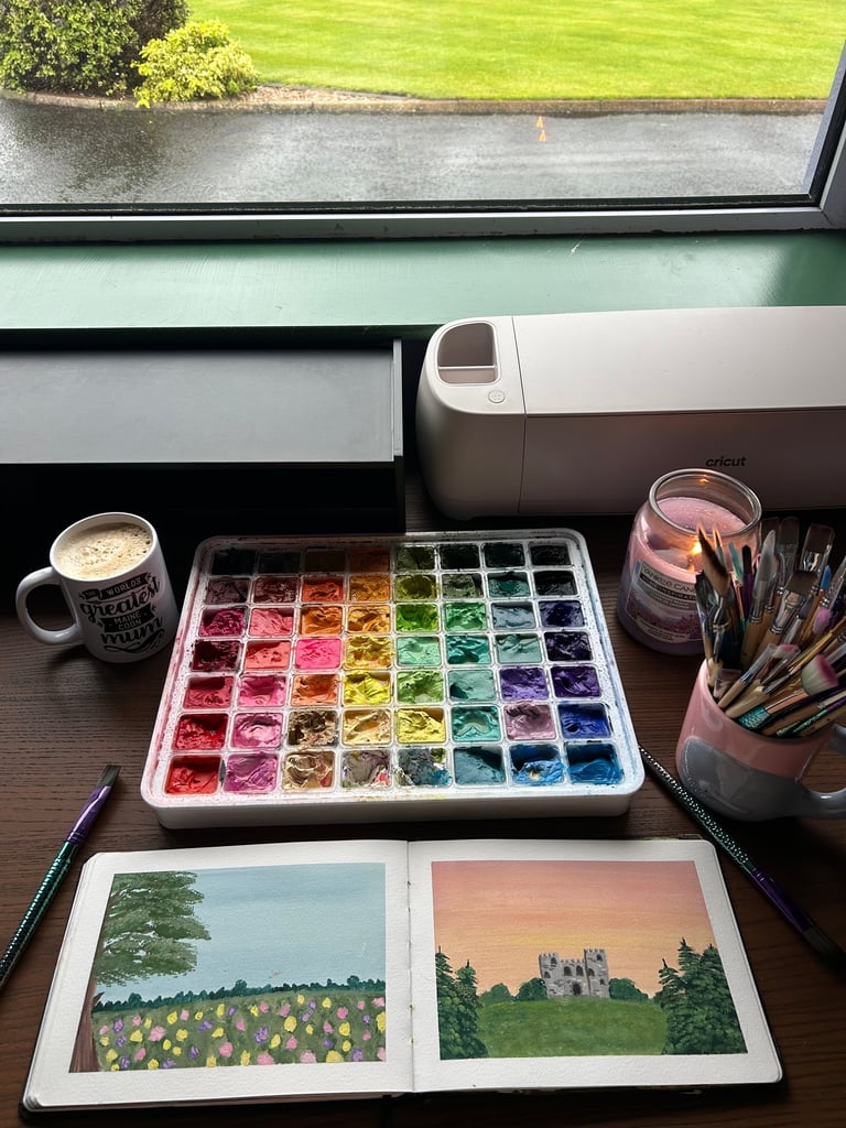 An image of coffee, a lit candle and some colourful paints