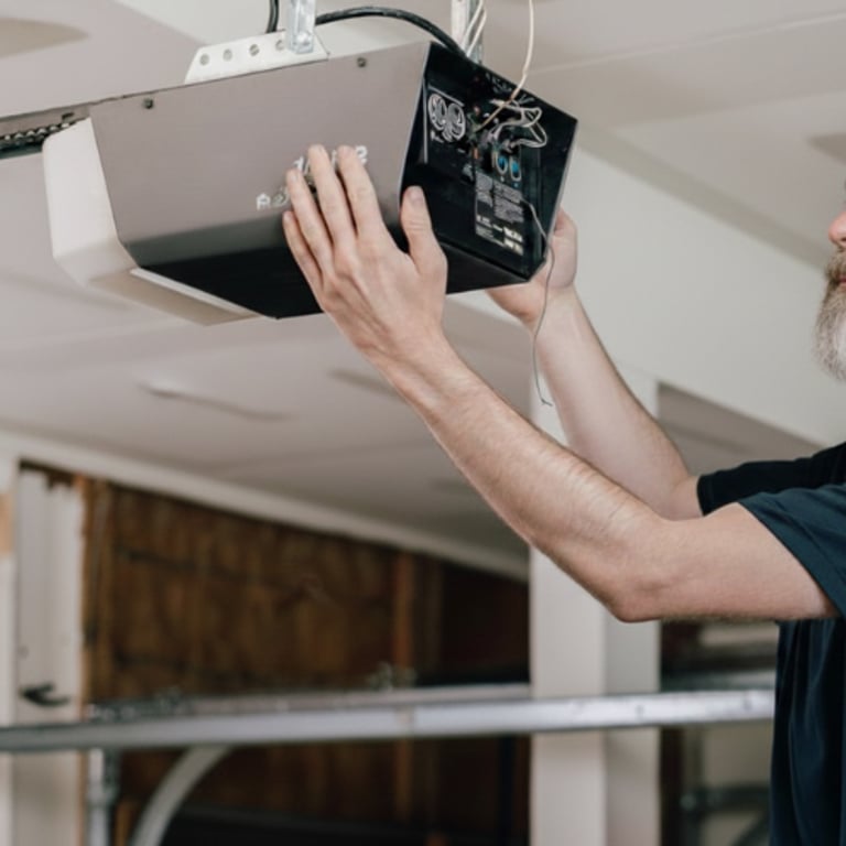 Professional technician performing a garage door opener repair and motor installation.