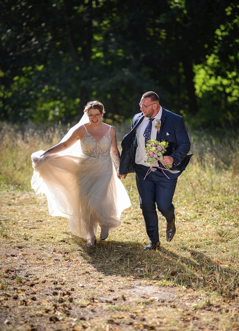 Brautpaar läuft Hand in Hand durch die Natur