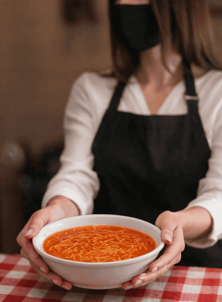 Mujer entregando plato de sopa aguada