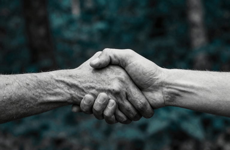 A high-contrast black and white photograph of two hands clasping, with a dark forest teal filter applied, representing alliance.