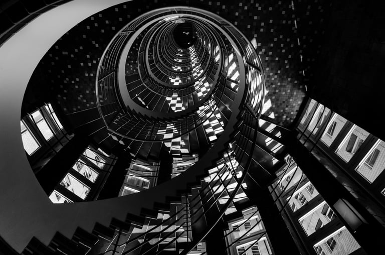 Stairs of Suspense - high-contrast geometric spiral stairwell photo by Martin Wacker, dramatic depth and shadow.