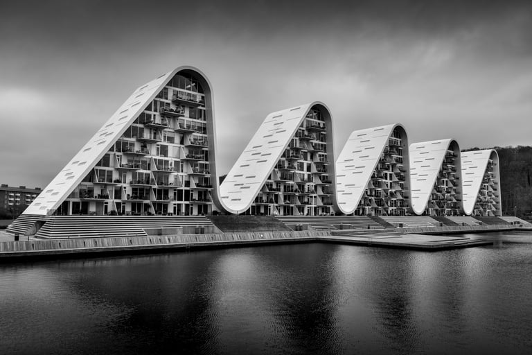 Wave-shaped building by Martin Wacker, sweeping white architectural curves reflected in calm water.