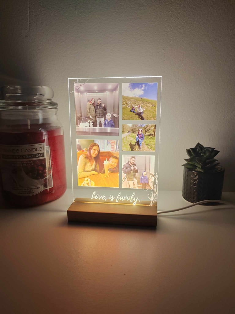Personalized LED photo frame night light with family pictures on a wooden base beside a candle.