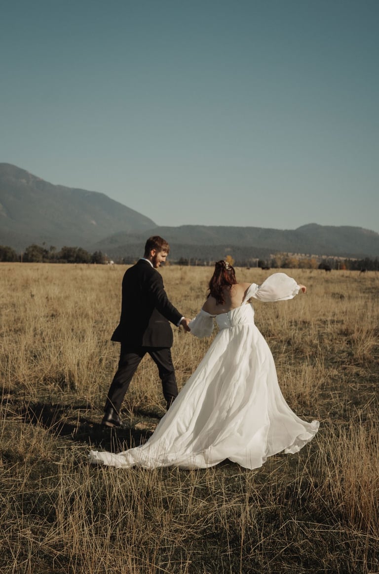 bride and groom portrait, walking, holding hands, Montana mountains, field