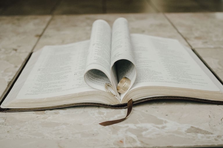 bible detail shot, pages folded into a heart with wedding bands inside