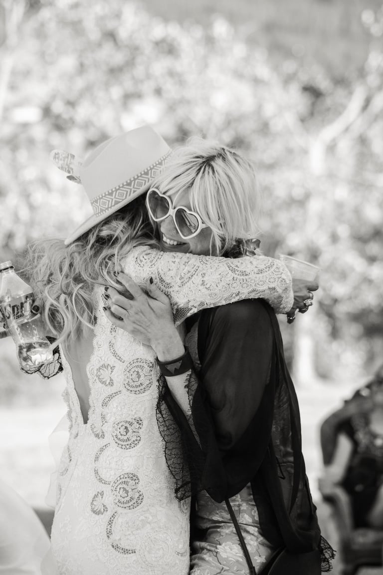 black and white photo of bride hugging a wedding guest