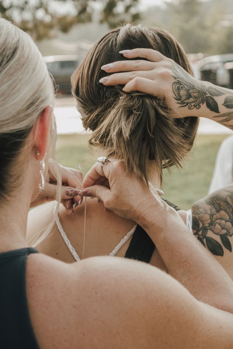 mother of the bride putting on bride's necklace