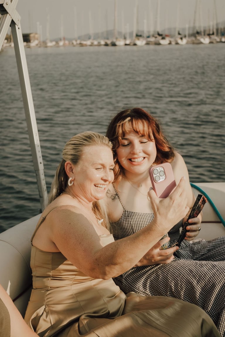 candid shot of wedding guests taking a selfie on a boat