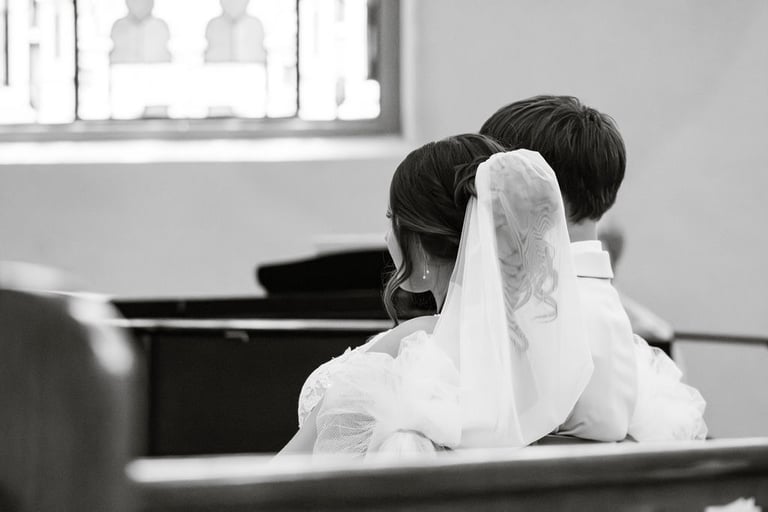 black and white shot of bride and groom from behind, sitting during Catholic ceremony