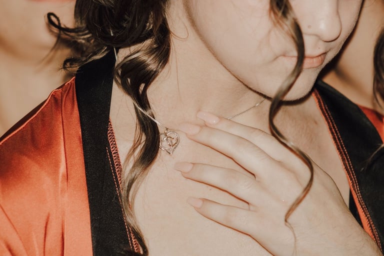 detail shot of bridesmaid putting on heart necklace
