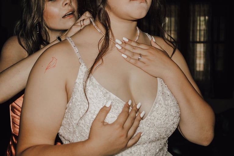 bridesmaid putting on bride's pearl necklace, white nails