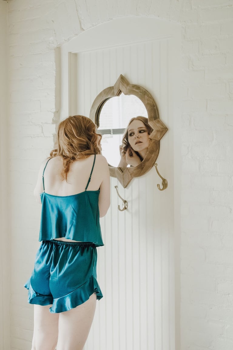 bridesmaid putting on earrings, looking in a mirror