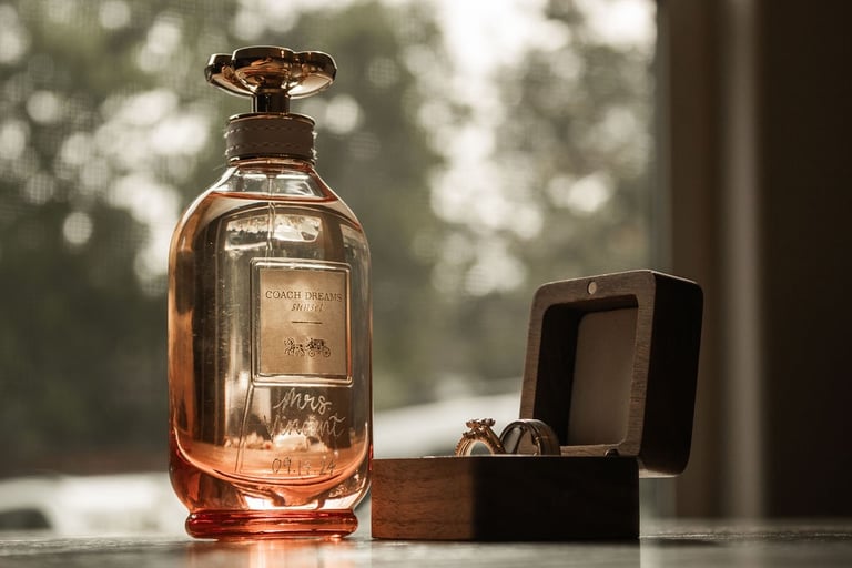 detail flat lay of perfume bottle, wooden wedding band box, and wedding rings
