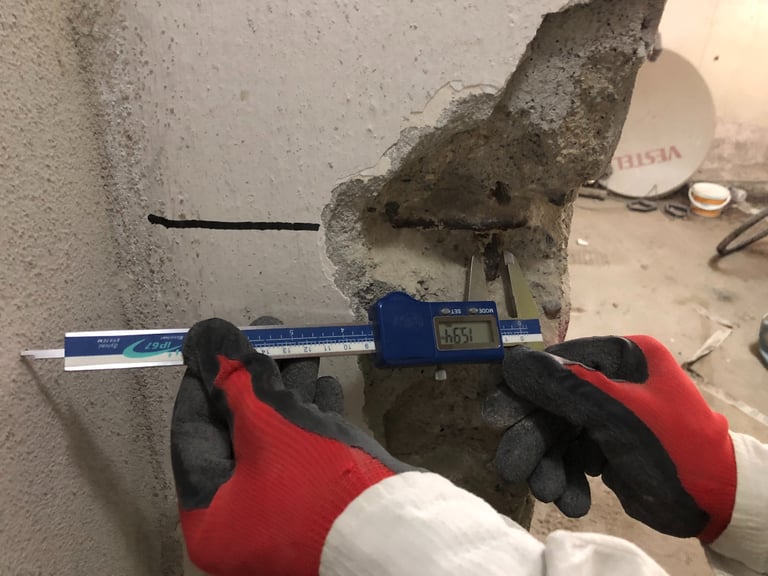 Yapısal inceleme için hasarlı bir beton kolon içindeki çelik donatıyı ölçen dijital kumpas.