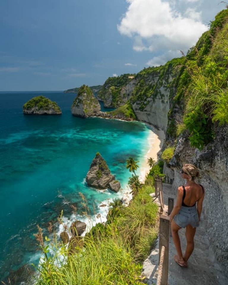 A woman overlooks the turquoise waters and cliffs of Diamond Beach in Nusa Penida, Bali.