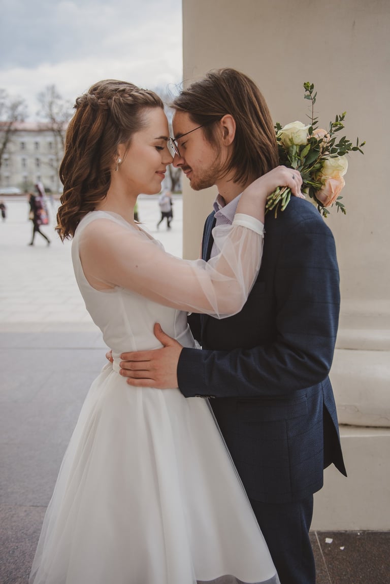 Jaunieji Vilniaus Katedros aiktėje, vestuvių fotosesija, nuotaka laiko puokštę, elegantiška suknelė
