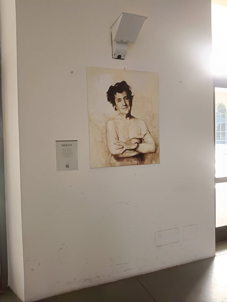 A sepia portrait painting of Alda Merini hanging on a white gallery wall in an art exhibit.