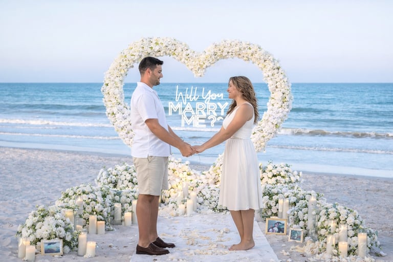 A romantic beach marriage proposal with a white floral heart arch, candles, and neon sign.