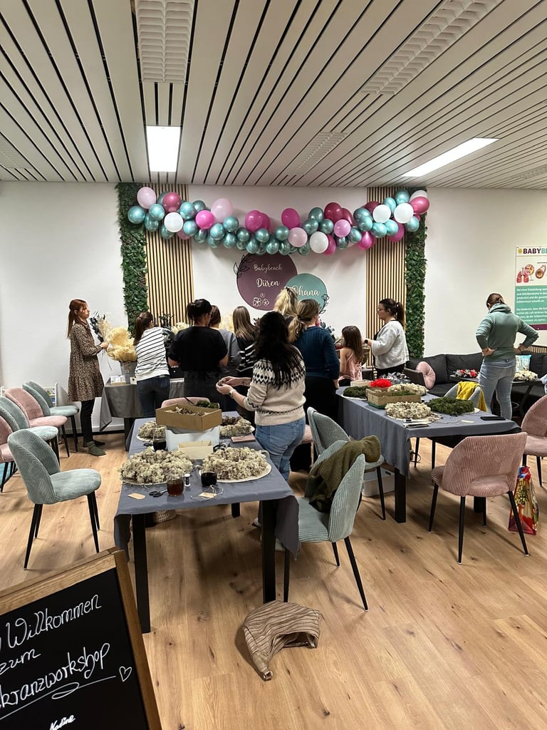 Women attending a creative floral wreath workshop at Babybeach Düren with balloon decorations.