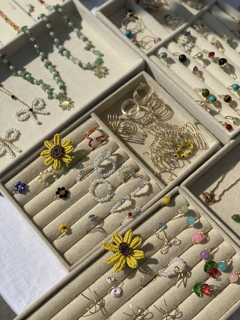 Handmade beaded jewelry featuring floral rings, and gold wire rings.