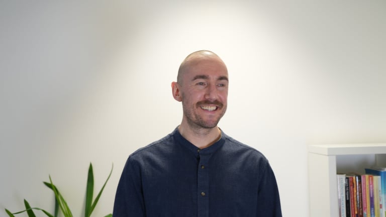 a bald man in a blue shirt smiling